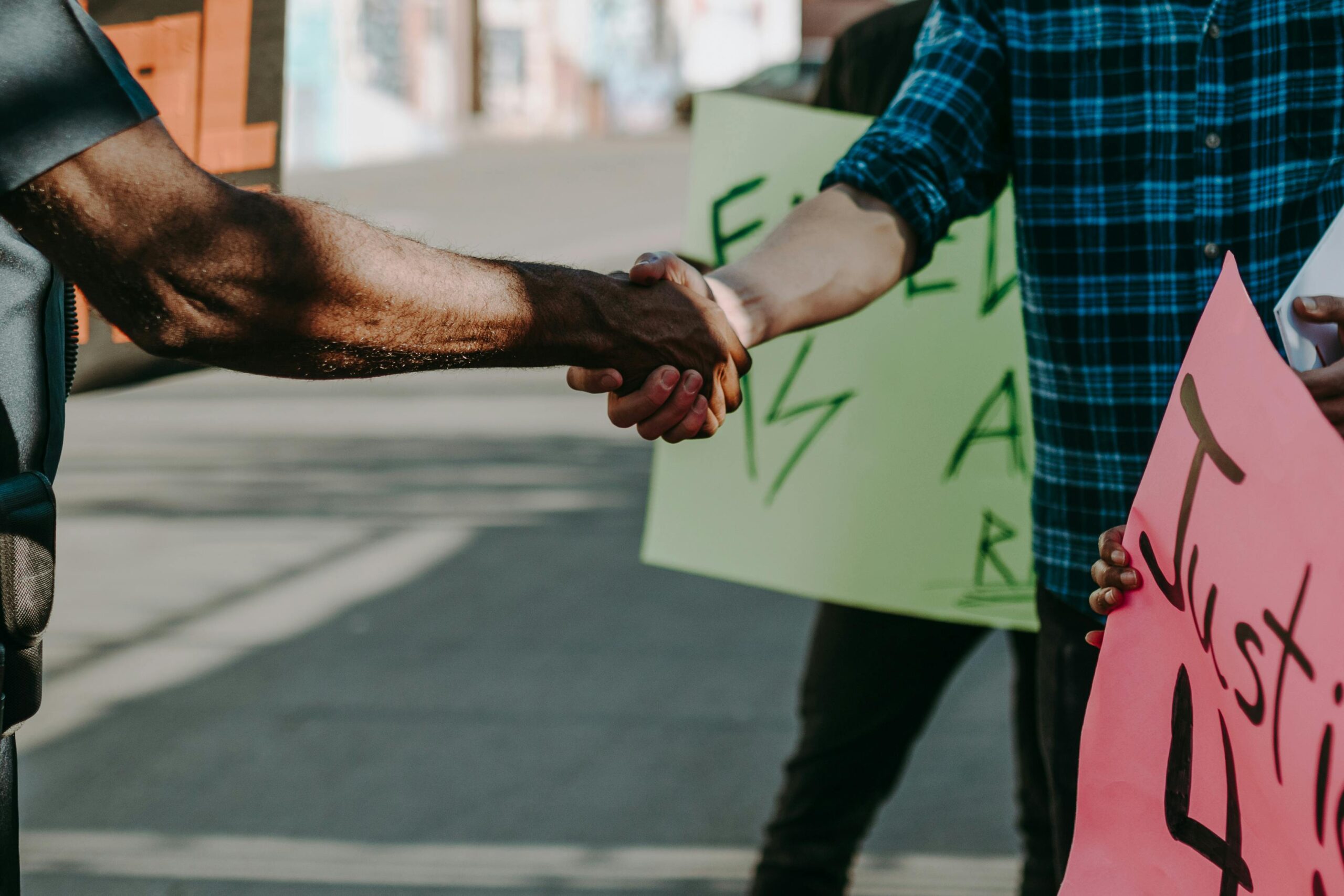 Close-up of a handshake between diverse individuals at a protest.